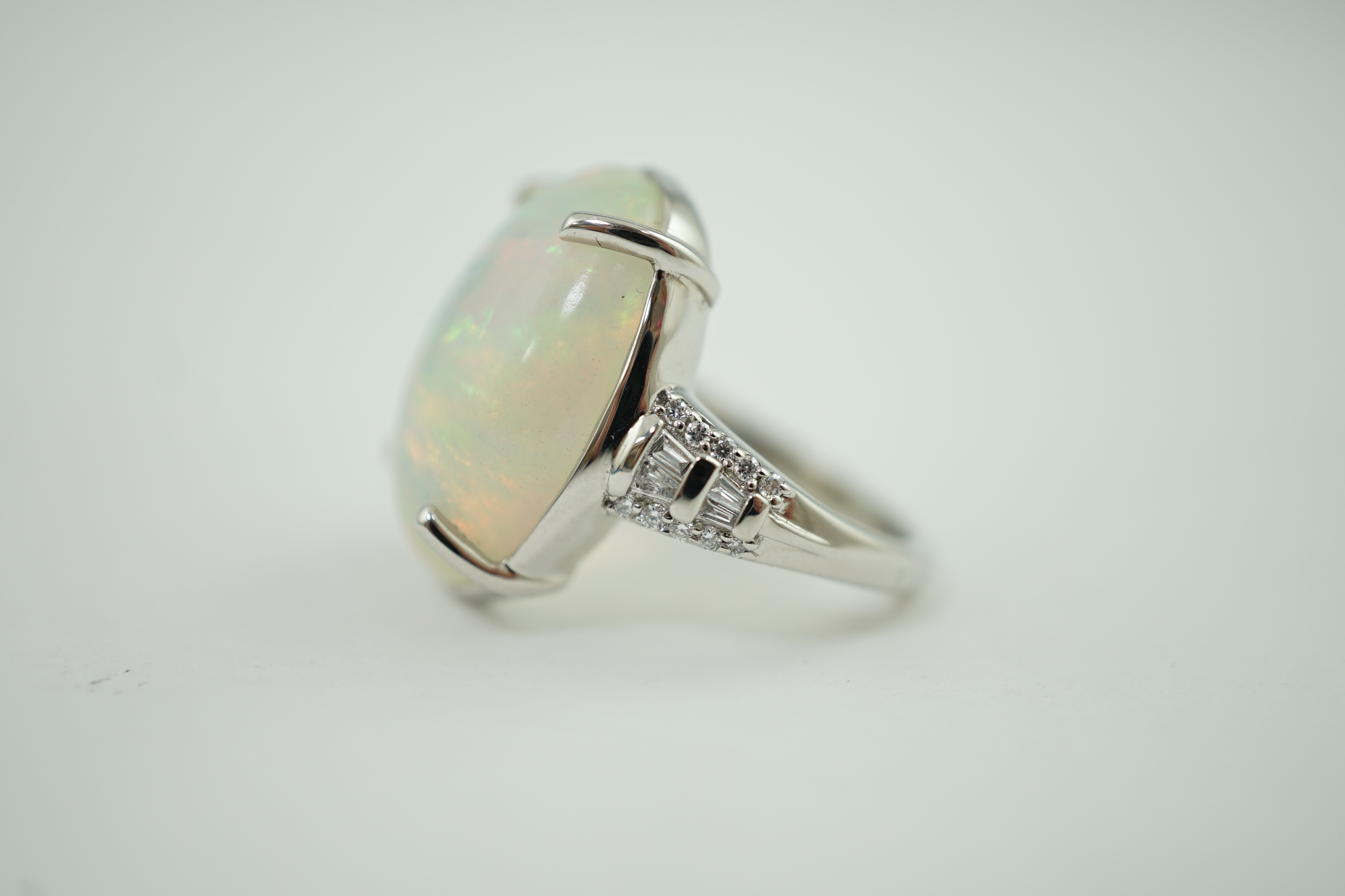 A modern Rhapsody platinum and opal white oval set dress ring, with trapeze and round cut diamond cluster set shoulders